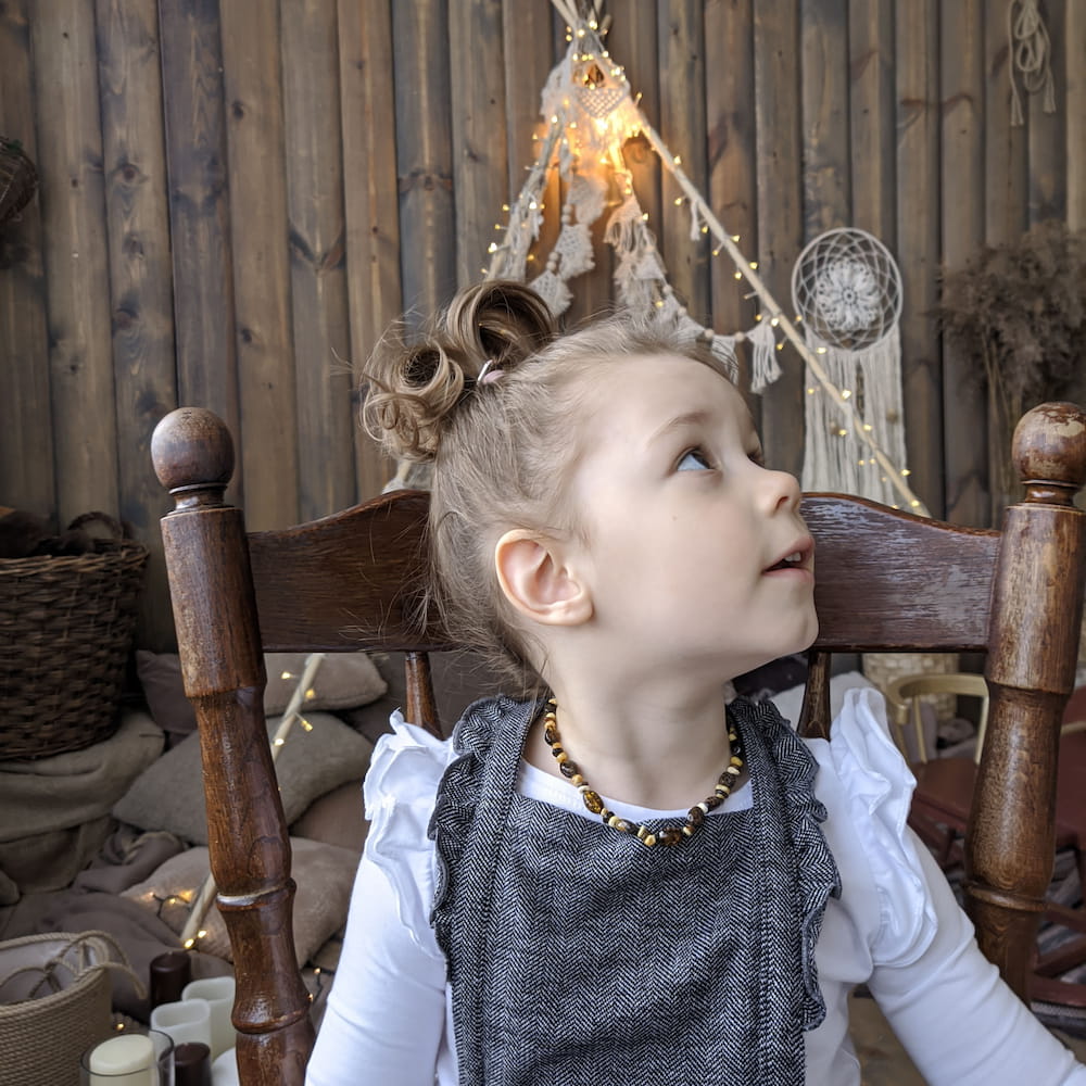 Cute baby girl wearing amber teething necklace